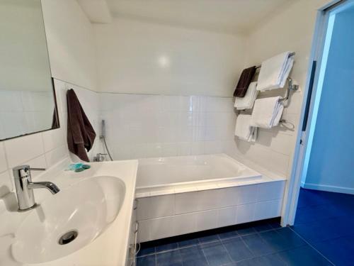 een witte badkamer met een wastafel en een bad bij Harbourside Lodge in Nelson