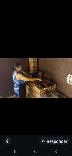 een vrouw die voor een bakstenen oven staat bij Chacara do Araujo in Mogi das Cruzes