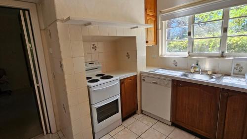 une petite cuisine avec une cuisinière et un évier dans l'établissement Griffin lakeside, à Yarralumla