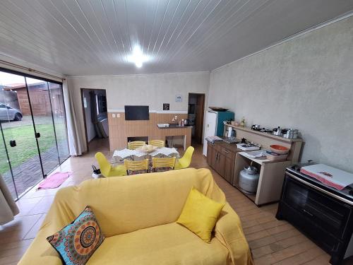 een woonkamer met een gele bank en een keuken bij Espaço artemísia in Tramandaí