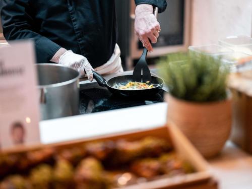 een persoon die voedsel kookt in een pan op een fornuis bij Mercure Chantilly Resort & Conventions in Chantilly