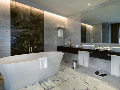 een badkamer met een ligbad en een wastafel bij Mövenpick Hotel du Lac Tunis in Tunis