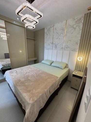 une chambre avec un grand lit et un lustre dans l'établissement Luxuoso Doce lar com Garagem, à Itapema