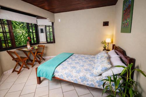 une chambre avec un lit, une table et des fenêtres dans l'établissement Suíte Iberê - Pousada Jussara, à Joinville