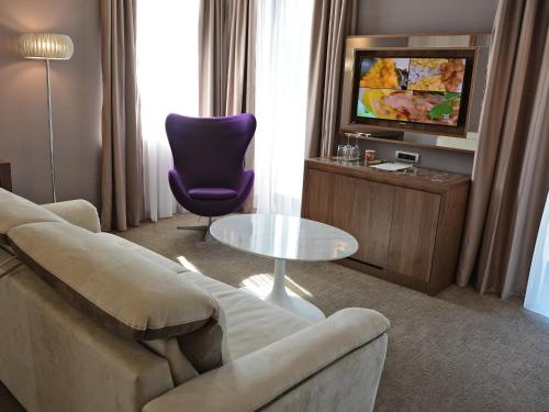 a living room with a couch and a table and a tv at Atlantida Boutique Hotel in Rogaška Slatina