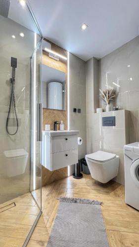 a bathroom with a toilet and a sink and a shower at Apartament Skandynawska Prostota z basenem i sauną in Kościelisko