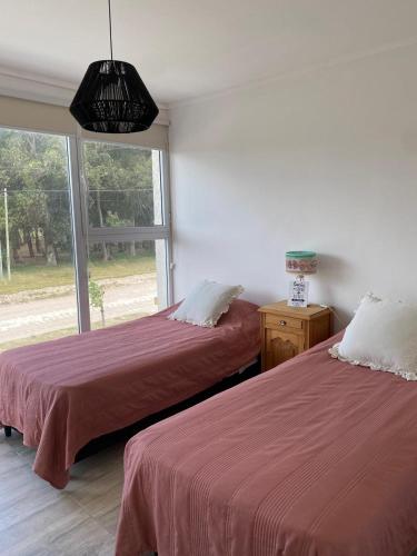 two beds in a room with a window at Duplex del Parque y Balneario in Necochea