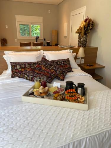 een dienblad met eten op een bed bij Koserê Exclusive Suites in Ilhabela