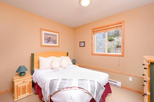 a bedroom with a bed and a window at Snowy Creek Chalet in Big White