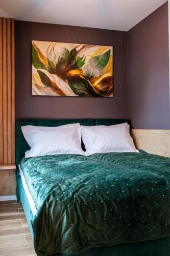 a bedroom with a green bed with two paintings on the wall at Sky Lux Cozy Nest in Jahorina