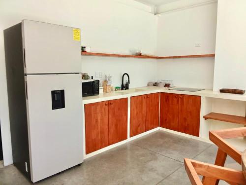 a kitchen with a white refrigerator and wooden cabinets at Jungle surf Villa in El Zonte