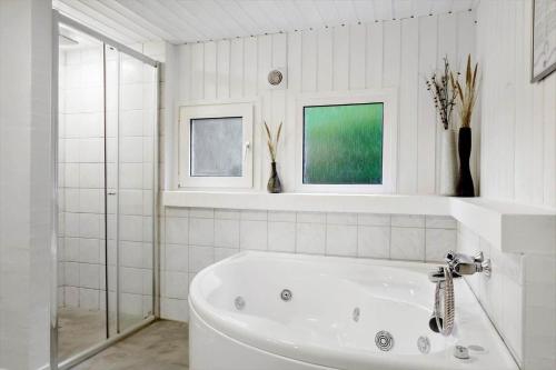 een witte badkamer met een bad en 2 ramen bij 990-Thisted-Spanggardsvej-29 in Torsted
