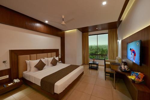 a bedroom with a bed and a flat screen tv at Lords Inn Somnath in Somnath