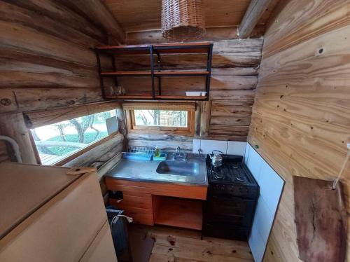 een keuken met een spoelbak en een fornuis in een klein huisje bij Los Lirios in Villa Giardino