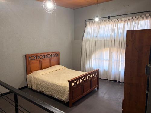 a bedroom with a wooden bed and a window at Departamento Loft Costanera in Gualeguaychú