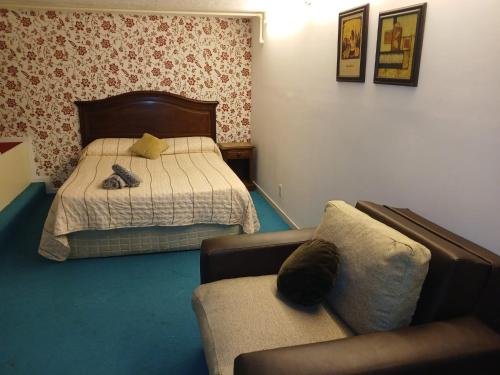 een slaapkamer met een bed, een bank en een stoel bij Espacio Acevedo familiar in Montevideo