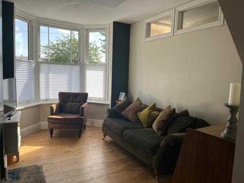 a living room with a couch and a chair and windows at Edwardian House in Stamford in Ryhall
