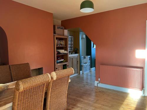a living room with orange walls and wicker chairs at Edwardian House in Stamford in Ryhall