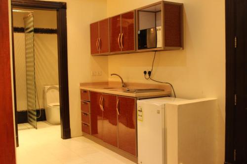 una pequeña cocina con fregadero y nevera. en Nozol Aram 3 Hotel Apartments, en Riad