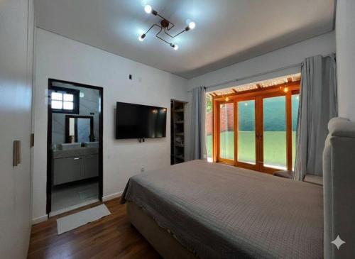 a bedroom with a bed and a large window at Pôr do Sol - Atibaia in Atibaia