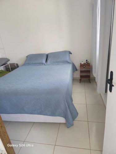 a bedroom with a bed with a blue comforter at Flat aconchegante em Itamaracá in Itamaracá