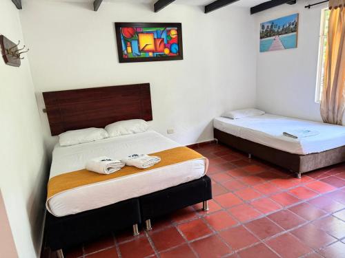 Twee eenpersoonsbedden in een kamer met een rode tegelvloer. bij Hotel Finca la Playa in Villeta