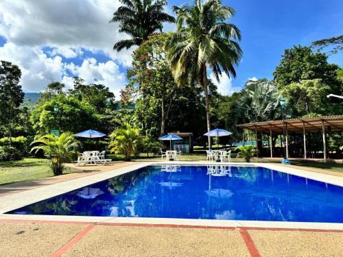 een zwembad met tafels en parasols in een resort bij Hotel Finca la Playa in Villeta