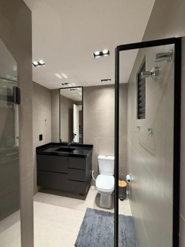 a bathroom with a toilet and a sink and a mirror at Studio Aconchegante no Number One Flat com vista mar in São Luís