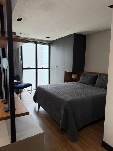 een slaapkamer met een bed en een groot raam bij Studio aconchegante no Number One Flat in São Luís