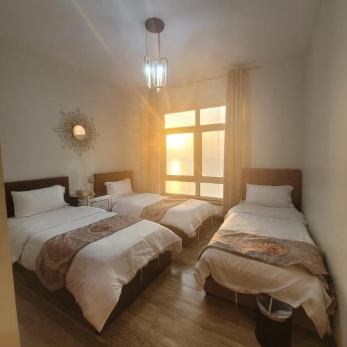 three beds in a room with a window at Royal Beach in King Abdullah Economic City