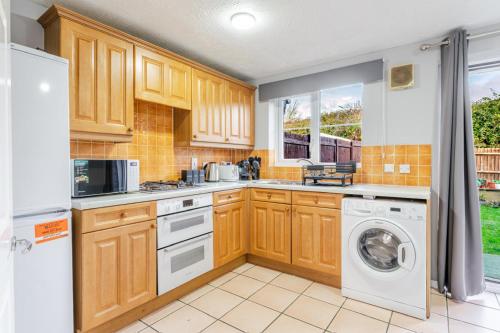 a kitchen with wooden cabinets and a washer and dryer at Modern Three Bedroom House Free parking wifi in Bristol