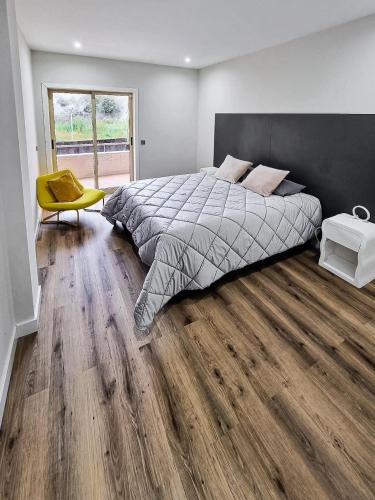 a bedroom with a large bed and a yellow chair at Spacious Home in Vila Nova de Gaia Porto