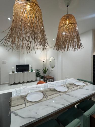 een eetkamer met een tafel met stoelen en 2 kroonluchters bij AT Alibaug - A Boho Boutique Stay in Alibaug