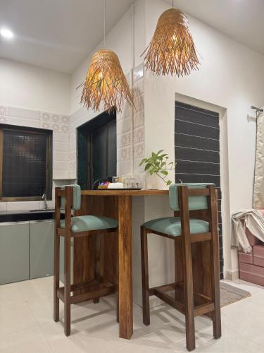 a kitchen with a wooden counter and two chairs at AT Alibaug - A Boho Boutique Stay in Alibaug