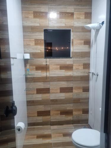 a bathroom with a toilet and a television on a wall at Chácara Bela Vista in Itajubá