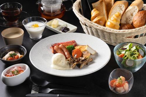a table with a plate of food and a basket of bread at KOS Restaurant & Hotel in Fujikawaguchiko