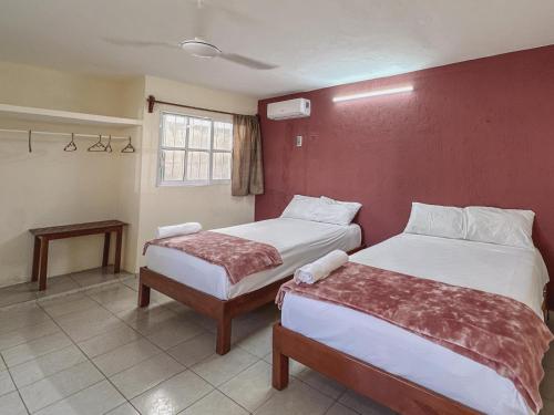 a bedroom with two beds and a red wall at Sol y Luna Hospedaje in Valladolid
