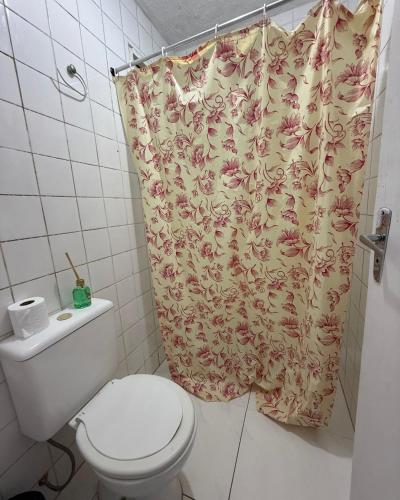 a bathroom with a toilet and a shower curtain at Casa completa Av Roberto da Silveira in Paraty