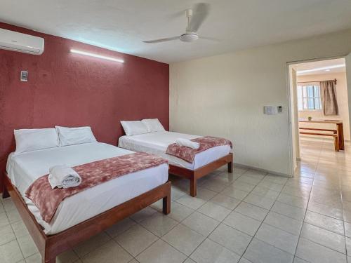 een slaapkamer met 2 bedden en een rode muur bij Sol y Luna Hospedaje in Valladolid