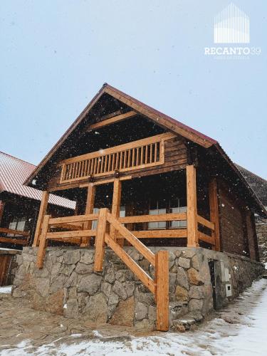 a large wooden barn with snow falling on it at Chalé Recanto 39 in Penhas da Saúde