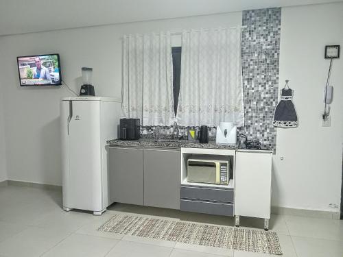 une cuisine avec un réfrigérateur et un micro-ondes dans l'établissement Casa das Cachoeiras, à Botucatu