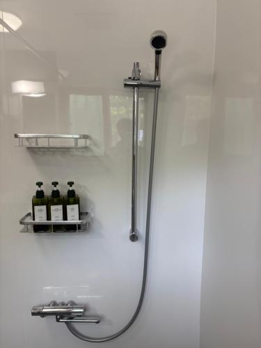 een douche in een badkamer met flessen op een plank bij Lodge Crea in Ujimi