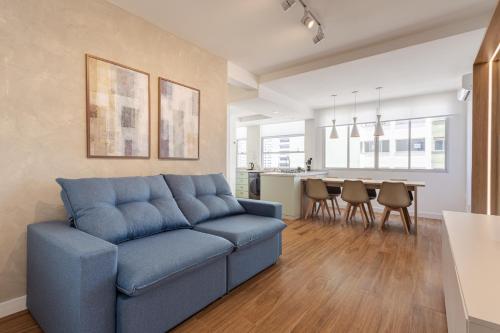a living room with a blue couch and a kitchen at Apto Reformado e Moderno com Vista Mar no Centro in Florianópolis