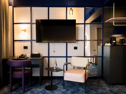 Cette chambre dispose d'un bureau, de deux chaises et d'une télévision. dans l'établissement Mercure Bucharest Cantemir, à Bucarest