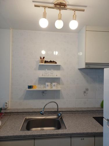 a kitchen with a sink and two lights above it at Melodia Pension in Geoje 