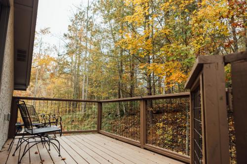 een houten terras met een bank en bomen bij Escape to Villa Serena - with a Hidden Speakeasy in Dahlonega