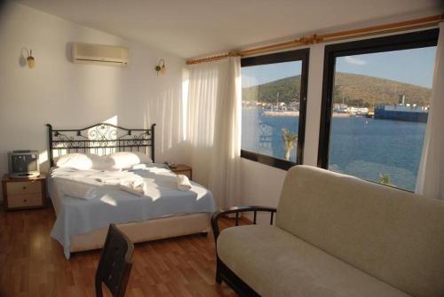 a bedroom with a bed and a couch and a large window at Kerman Hotel in Cesme