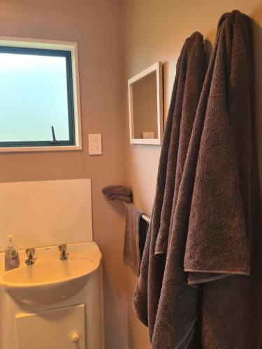 een badkamer met een handdoek die naast een wastafel hangt bij Lanark Mews in Te Kopuru