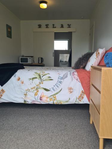 een bed met een deken erop bij Lanark Mews in Te Kopuru