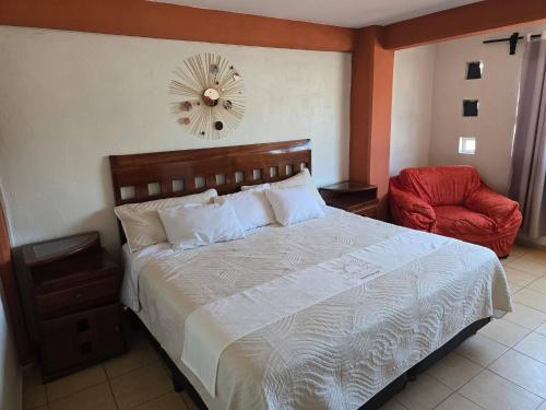 a bedroom with a large bed and a red chair at Loft Rayito de Sol, Zihuatanejo Center with AC in Zihuatanejo